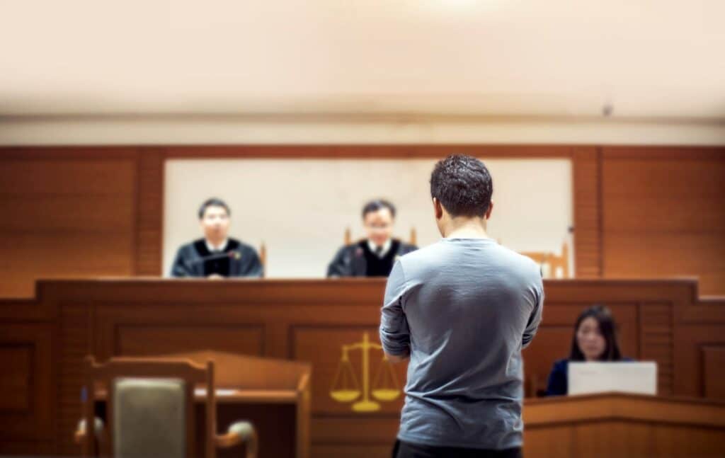 Que faire après une licence de droit ? Deux magistrats et une greffière dans une salle de tribunal, face à une personne debout.